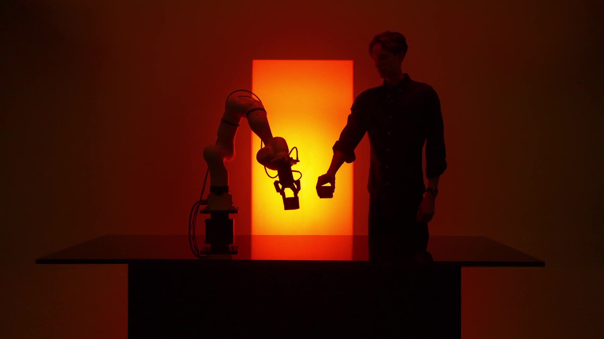 A person hands a part to a Machenta robot arm in the lab