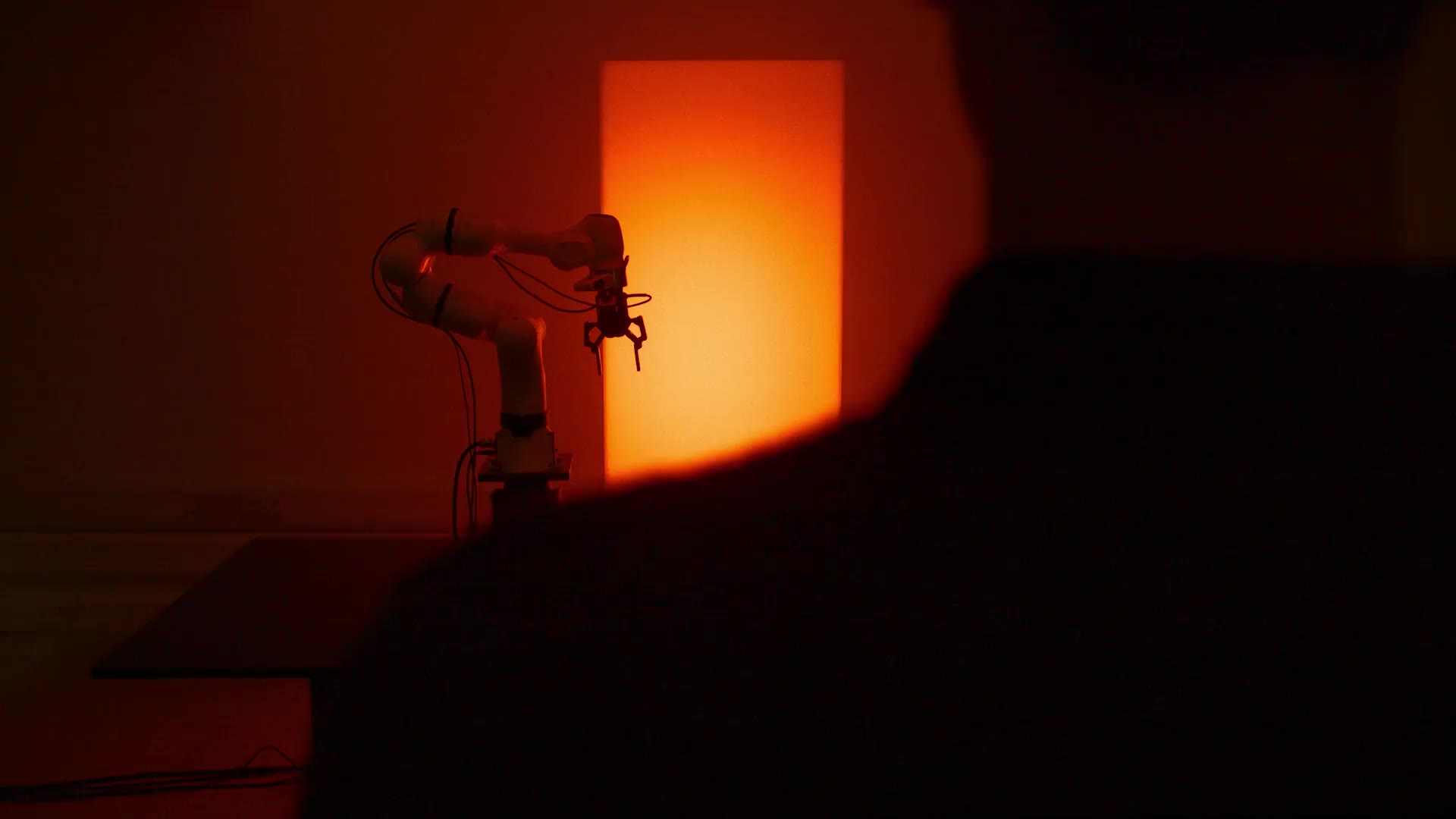 A Machenta robot arm in the lab, lit by a column of orange light